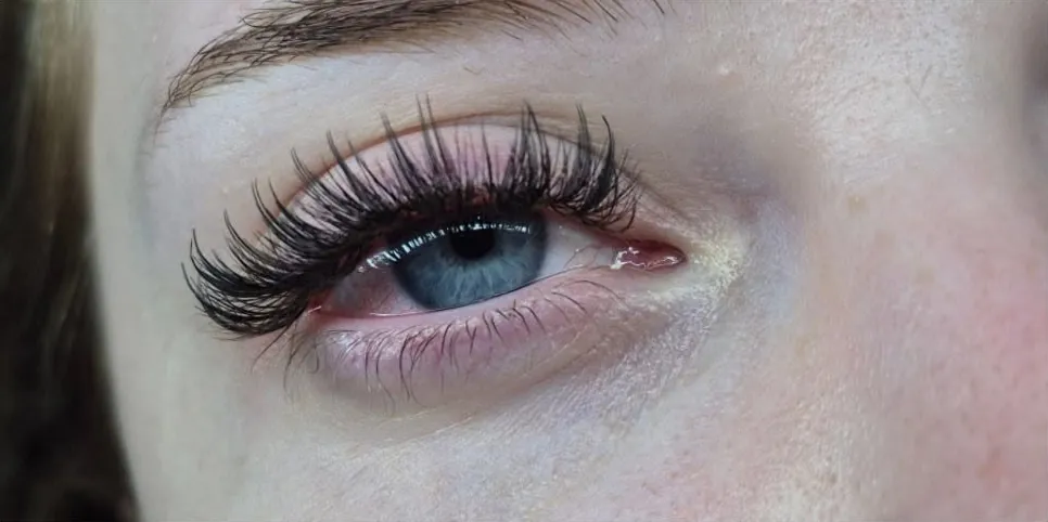 Close-up of a client's blue eye with a full, fluffy set of lash extensions by Mona