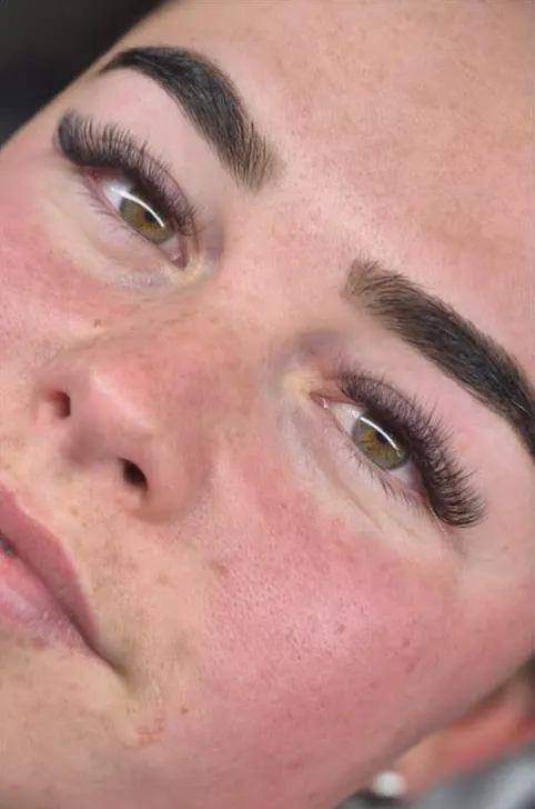 A client with brown eyes looking up, wearing a dark, defined set of lash extensions
